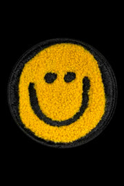 Smiley face patch with yellow background and black outline on a black background