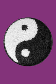 Yin and yang symbol on a textured round patch with a purple background