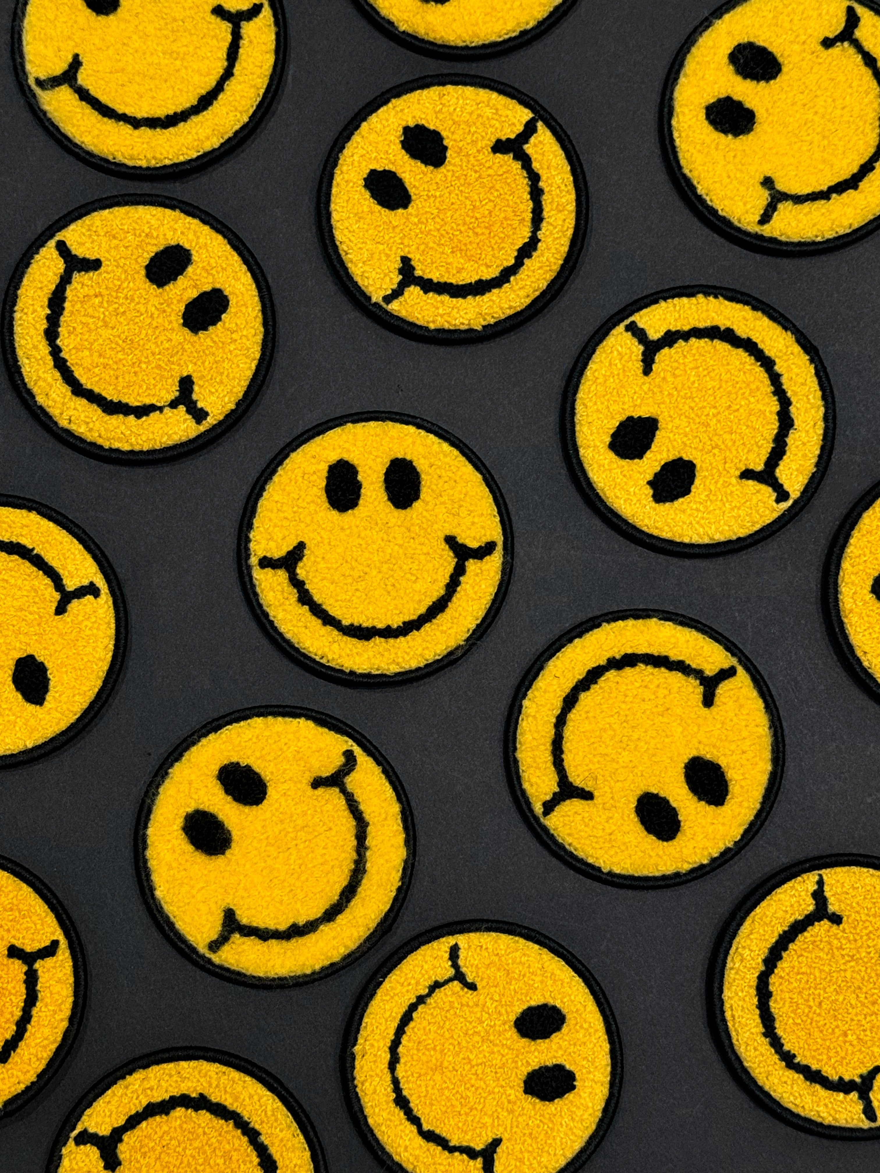 Pattern of yellow smiley face patches on a black background