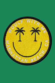 Smiley face patch with palm trees and text on a green background