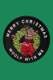 A round embroidered patch with a reindeer, Christmas trees, and the text 'Merry Christmas Woolf With Me' on a black background with a velcro backing.