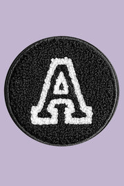 Black round patch with white letter 'A' on a purple background