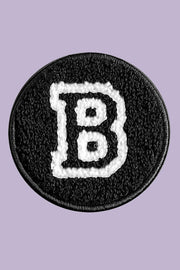 Black patch with white letter 'B' on a purple background