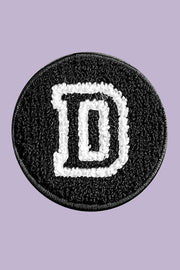 Black patch with white letter 'D' on a purple background