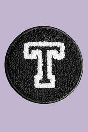 Black patch with white letter 'T' on a purple background