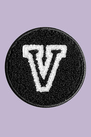 Black patch with a white 'V' symbol on a purple background
