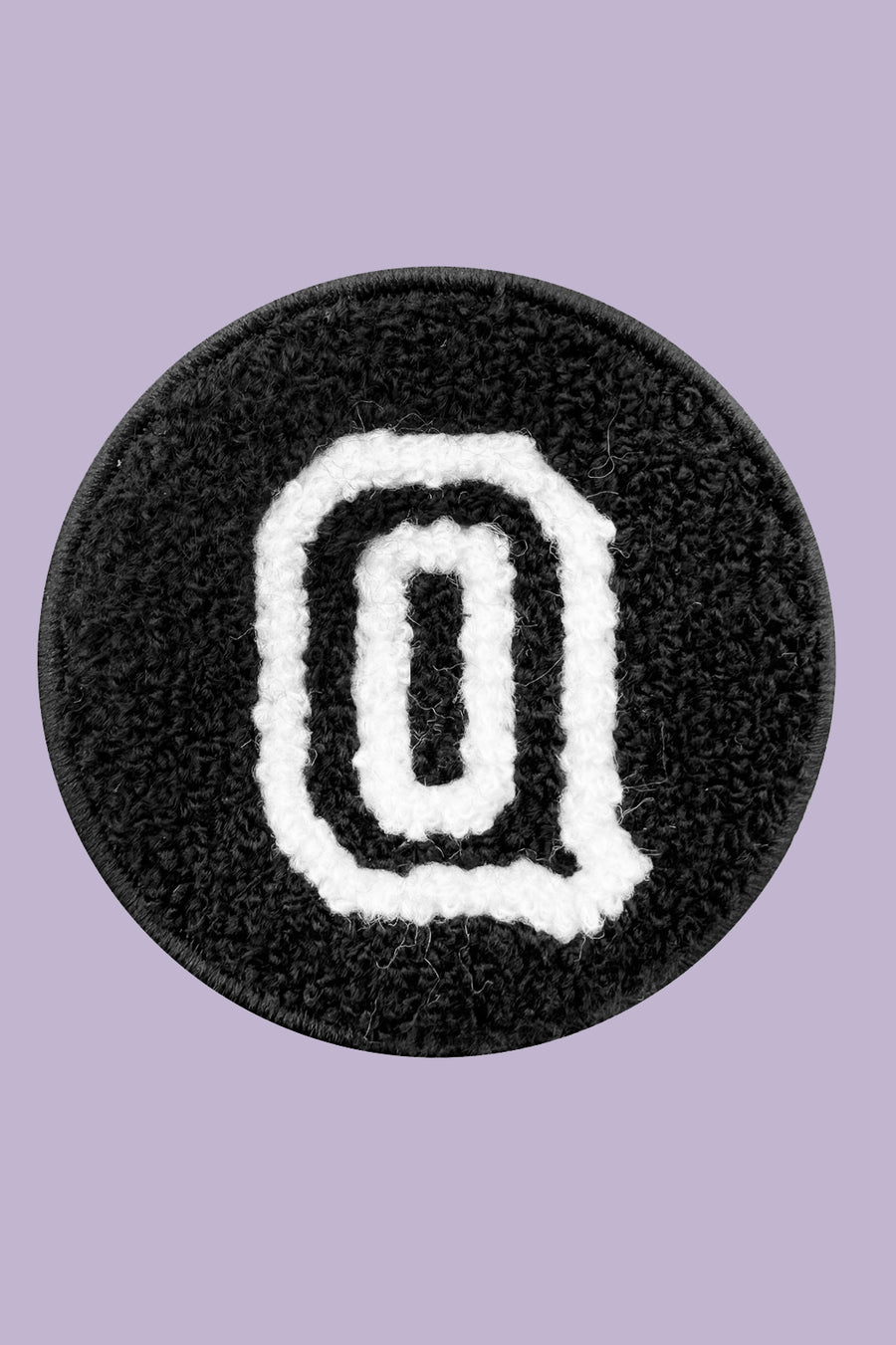 Black circular patch with a white letter 'Q' on a purple background