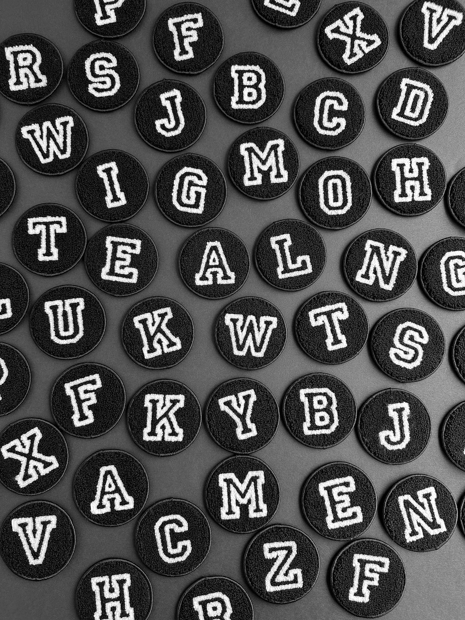 Black round stickers with white letters arranged in a grid on a gray background