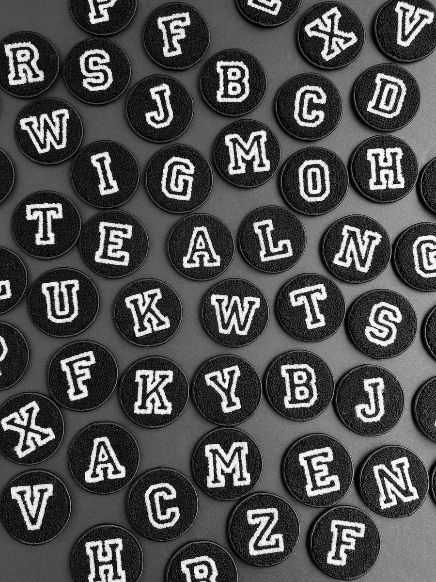 Black round stickers with white letters arranged in a grid on a gray background