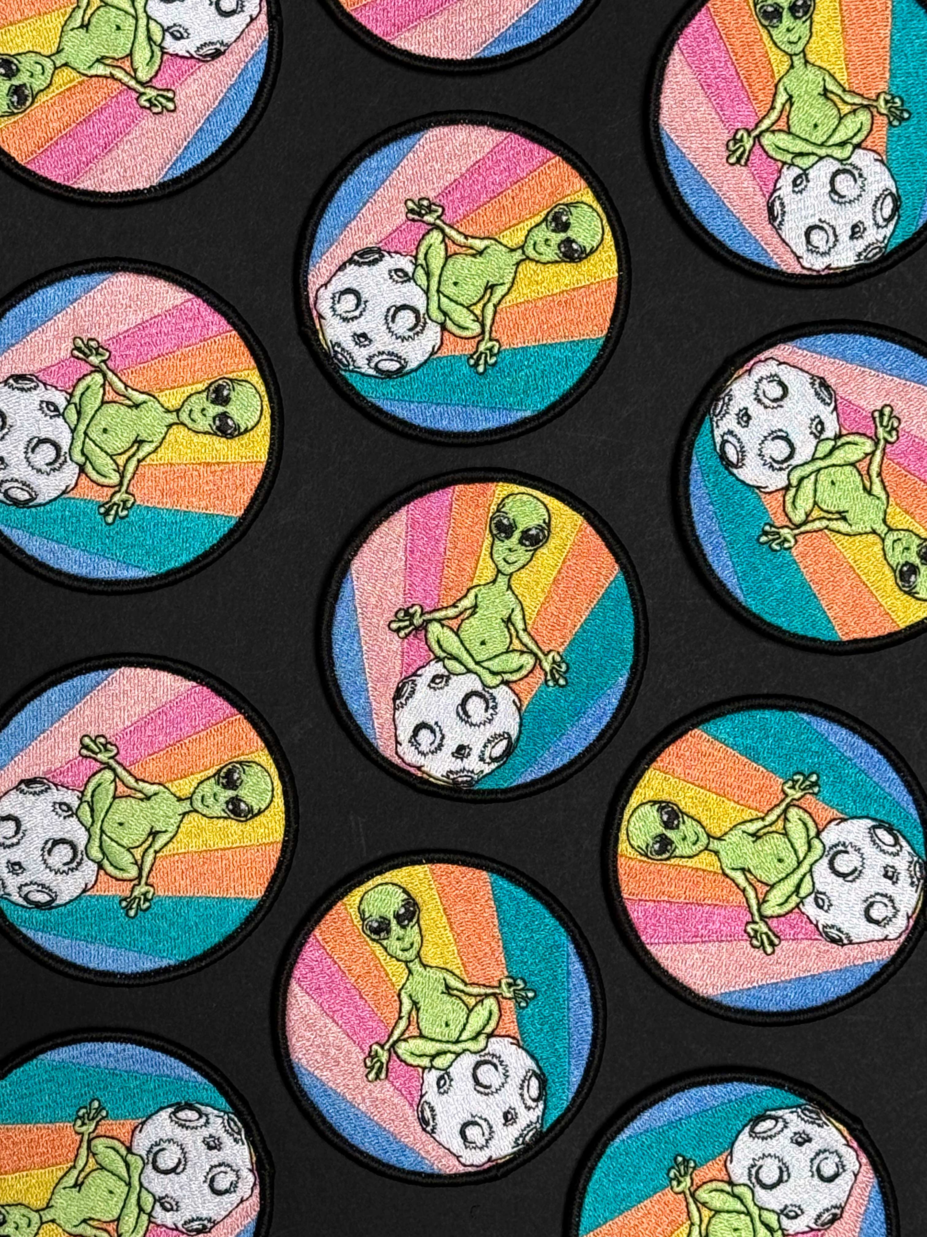 Sticker design with green alien and frog characters on colorful backgrounds.