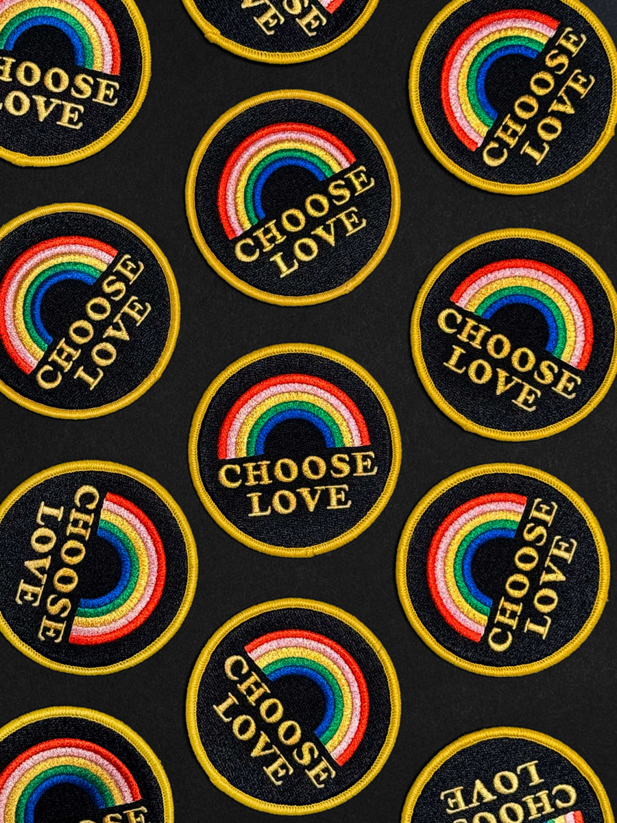 Pattern of rainbow and 'Choose Love' patches on a black background