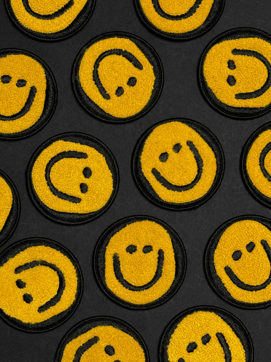 Pattern of yellow smiley face patches on a black background