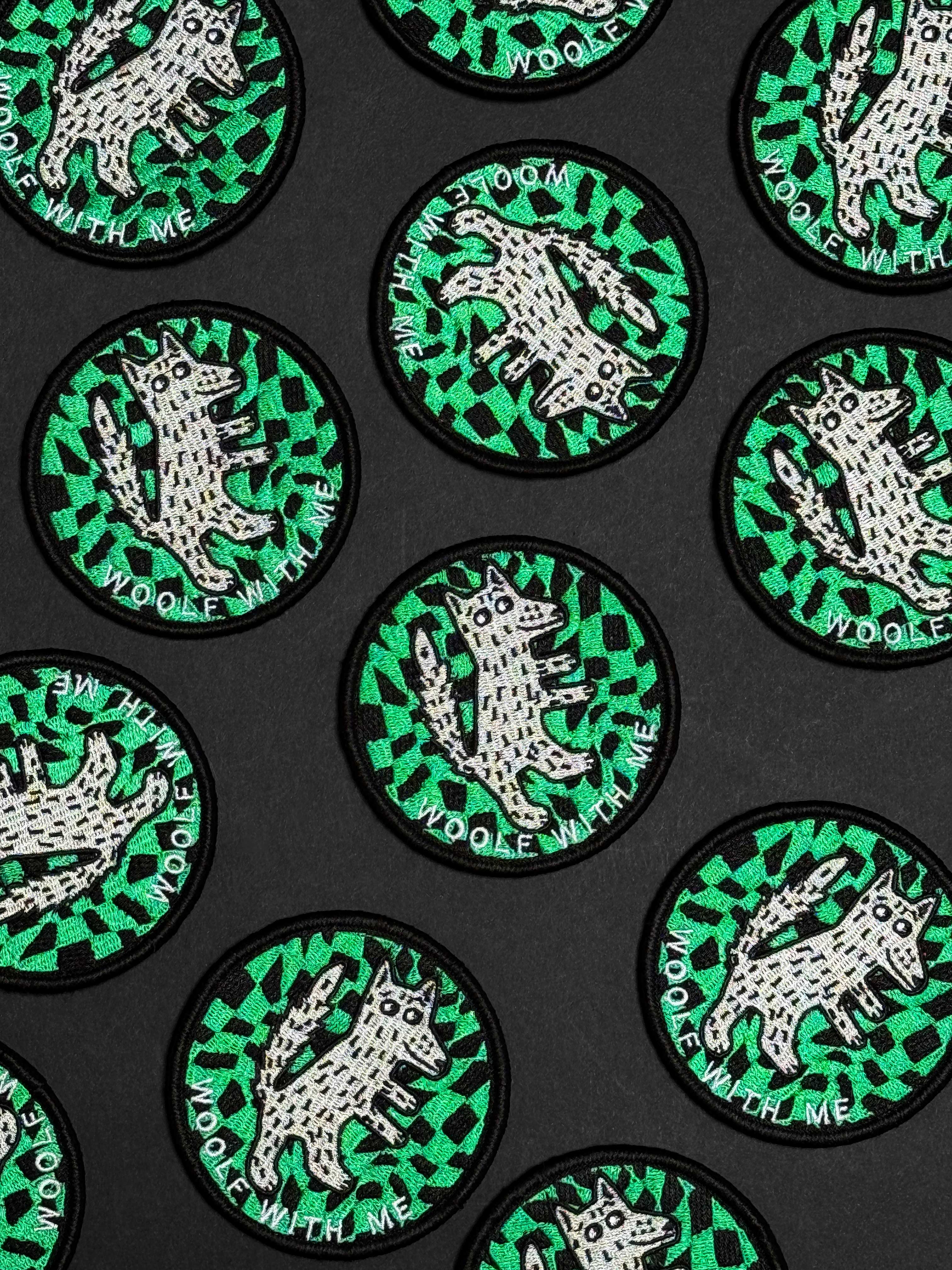 Circular patches with a wolf design on a green and black patterned background