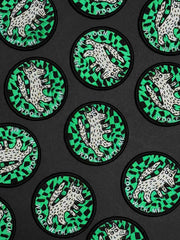 Circular patches with a wolf design on a green and black patterned background