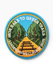 Woolf With Me® custom circular embroidered Velcro patch featuring a railway track through a forest scene.