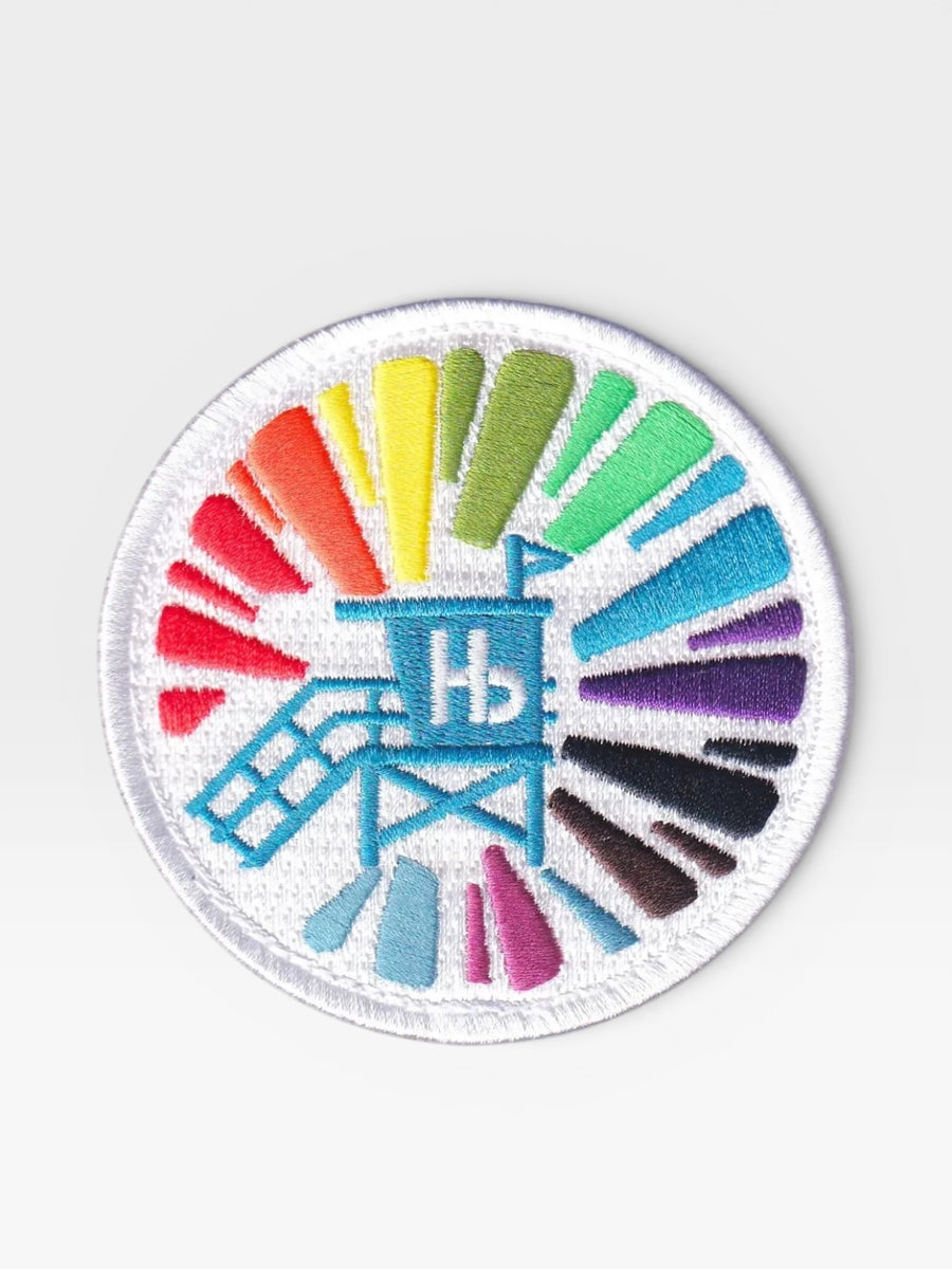 Woolf With Me® custom circular embroidered velcro patch featuring a blue lifeguard tower and colorful sunburst design.